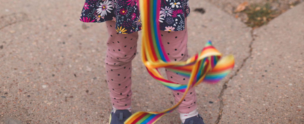 A child's legs in leggins holding a ribbon toy
